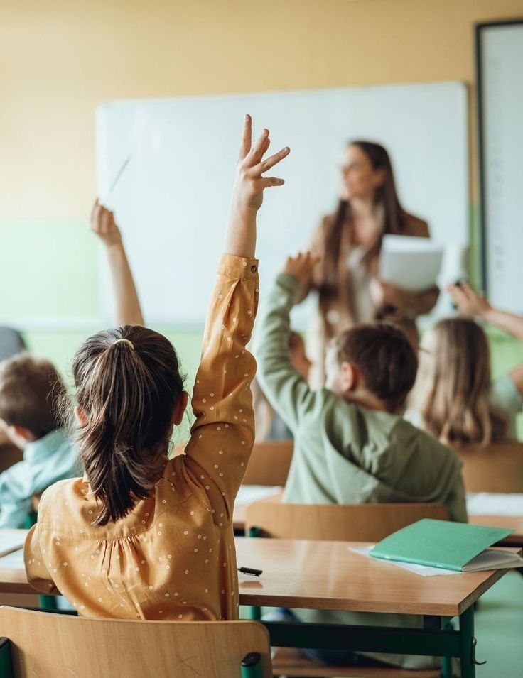 Alunos em sala de aula com a mão levantada